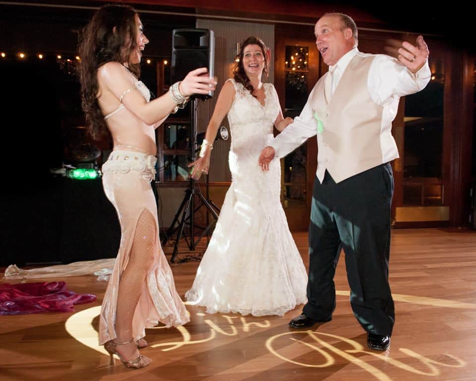 Carrara Nour, a belly dancer in Orlando, dances with the newlyweds at their Lake Mary, FL wedding at Timacuan Country Club